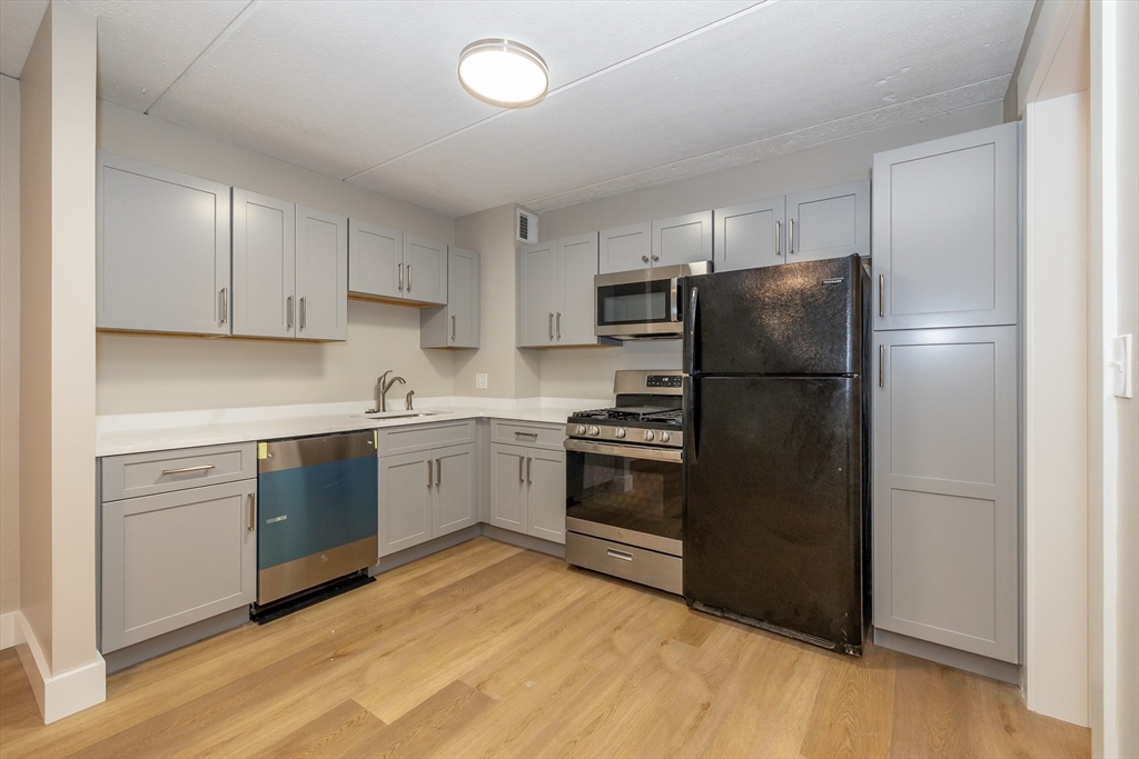 1500 Worcester Road, Unit 217 Framingham, MA 01702 - Photo 12 of 37 a kitchen with a refrigerator cabinets and wooden floor