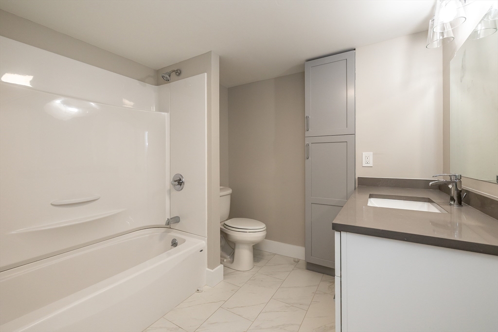 1500 Worcester Road, Unit 217 Framingham, MA 01702 - Photo 22 of 37 a bathroom with a granite countertop sink toilet and shower