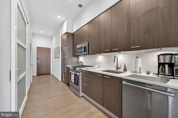 a kitchen with stainless steel appliances a sink a stove a refrigerator cabinets and a counter top space