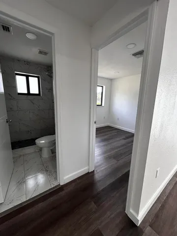 a view of an empty room with wooden floor and a window