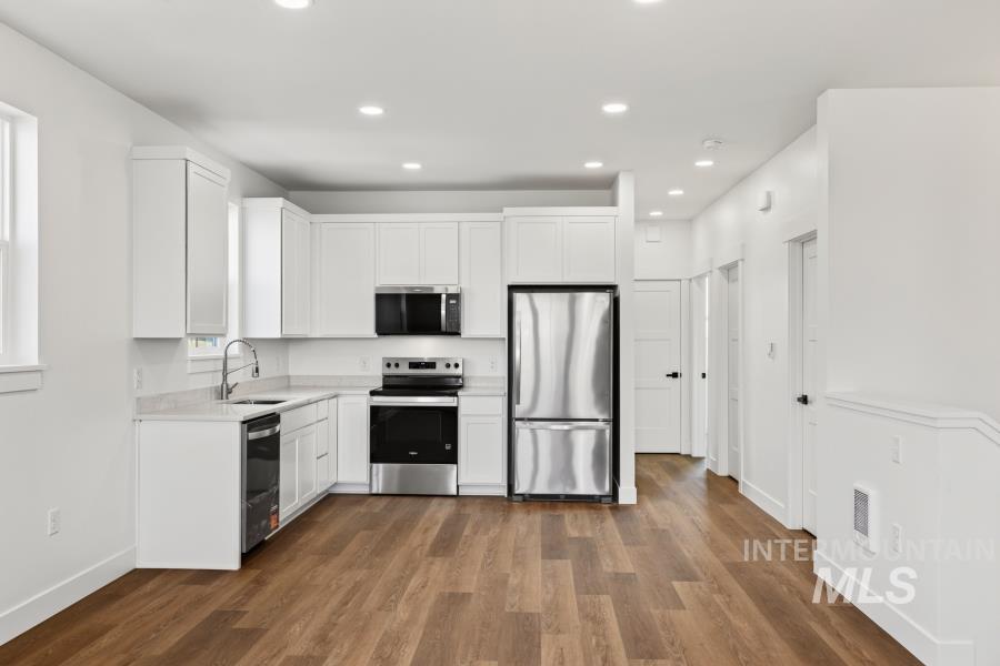 1298 Edington Moscow, ID 83843 - Photo 10 of 32 Kitchen featuring white shaker cabinetry, stainless steel appliances, wood-finish flooring, recessed lighting, and light-colored countertops