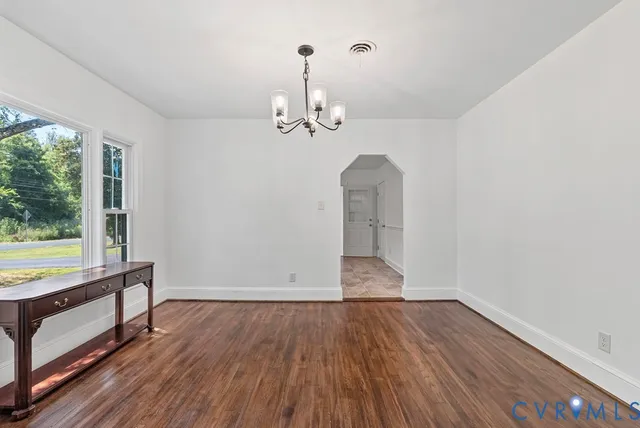 a view of an empty room with window wooden floor and a kitchen