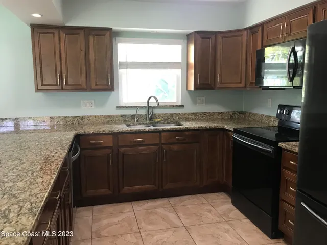 a kitchen with granite countertop a sink window and cabinets