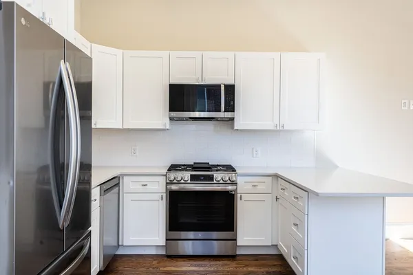 a kitchen with stainless steel appliances granite countertop a stove and a wooden floor