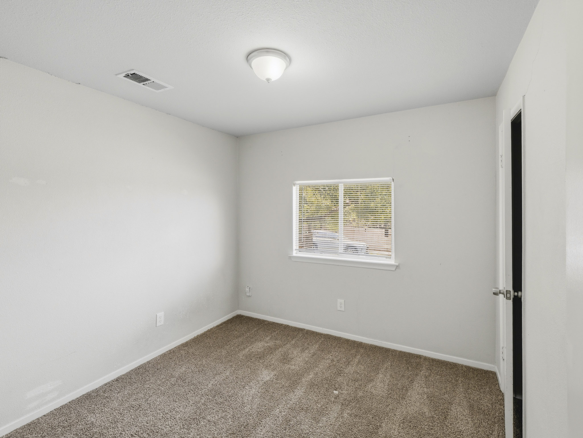 2401 Burleson Road Austin, TX 78741 - Photo 23 of 25 Well-lit room, ideal for flexible arrangements, with plush carpeting and a bright window.