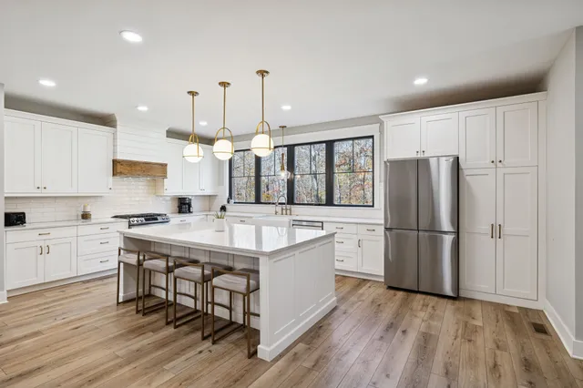 a kitchen with kitchen island a white counter top space stainless steel appliances and cabinets
