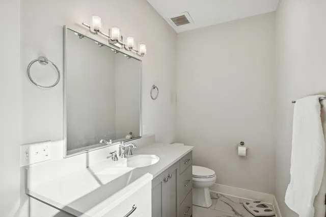 a bathroom with a granite countertop toilet sink and mirror