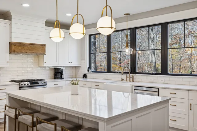 a kitchen with stainless steel appliances granite countertop a sink a stove and a white cabinets