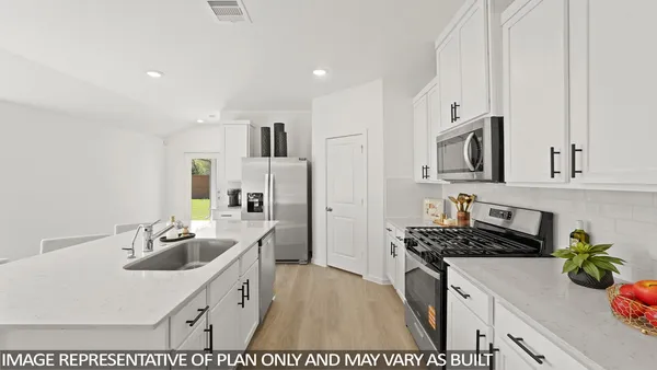 a living room with stainless steel appliances furniture a flat screen tv and a kitchen view