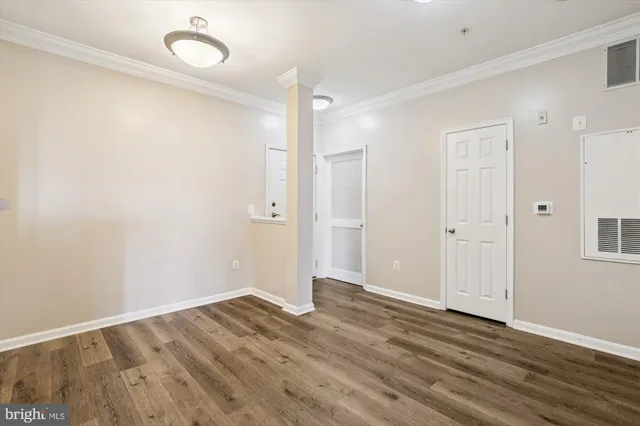 a view of an empty room with wooden floor and windows