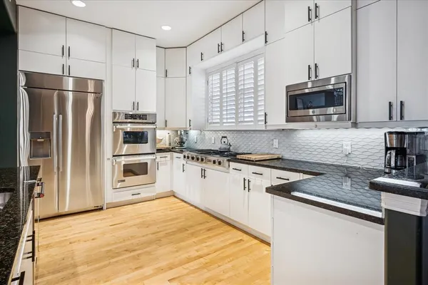 a kitchen with granite countertop a refrigerator stove and microwave