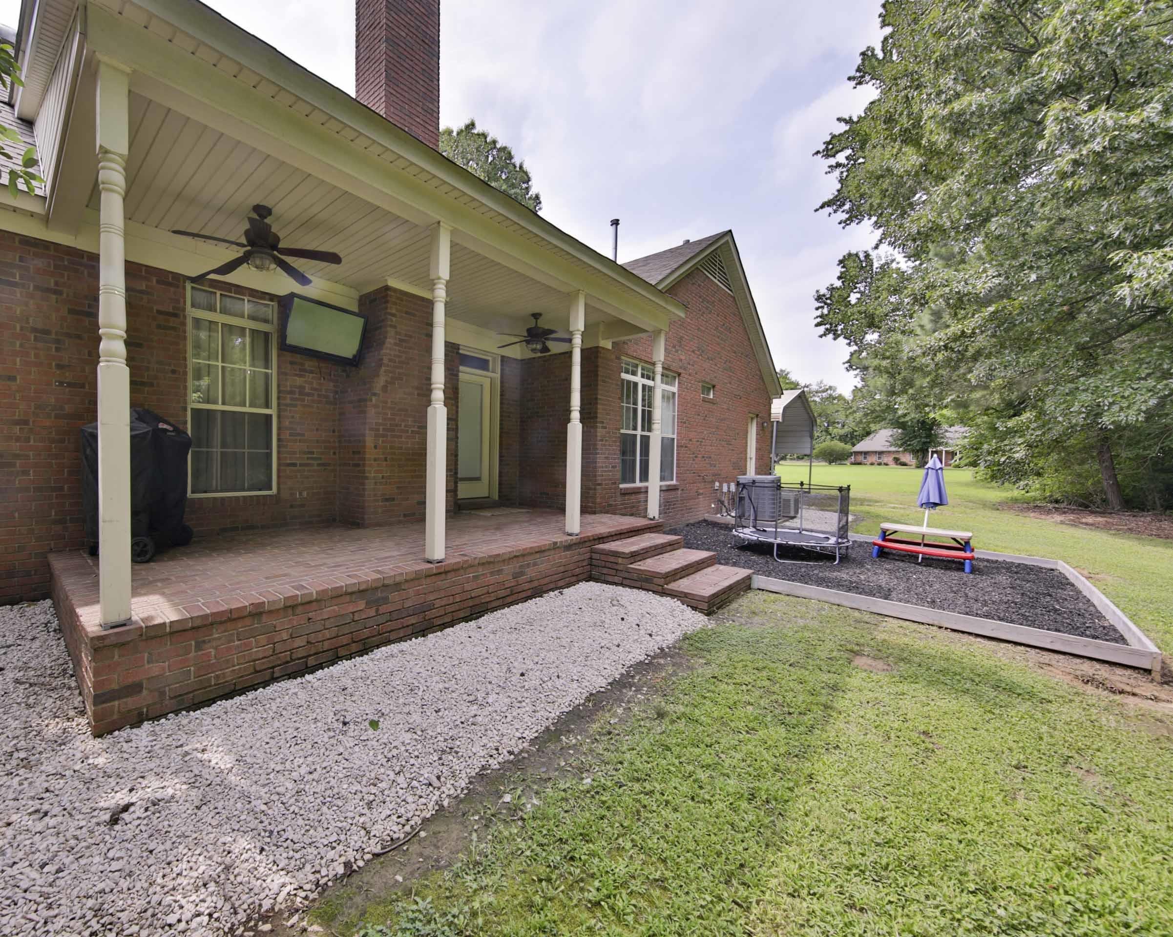 104 Miller Road Covington, TN 38019 - Photo 6 of 25 Brick exterior with a covered patio, featuring two ceiling fans and a mounted television