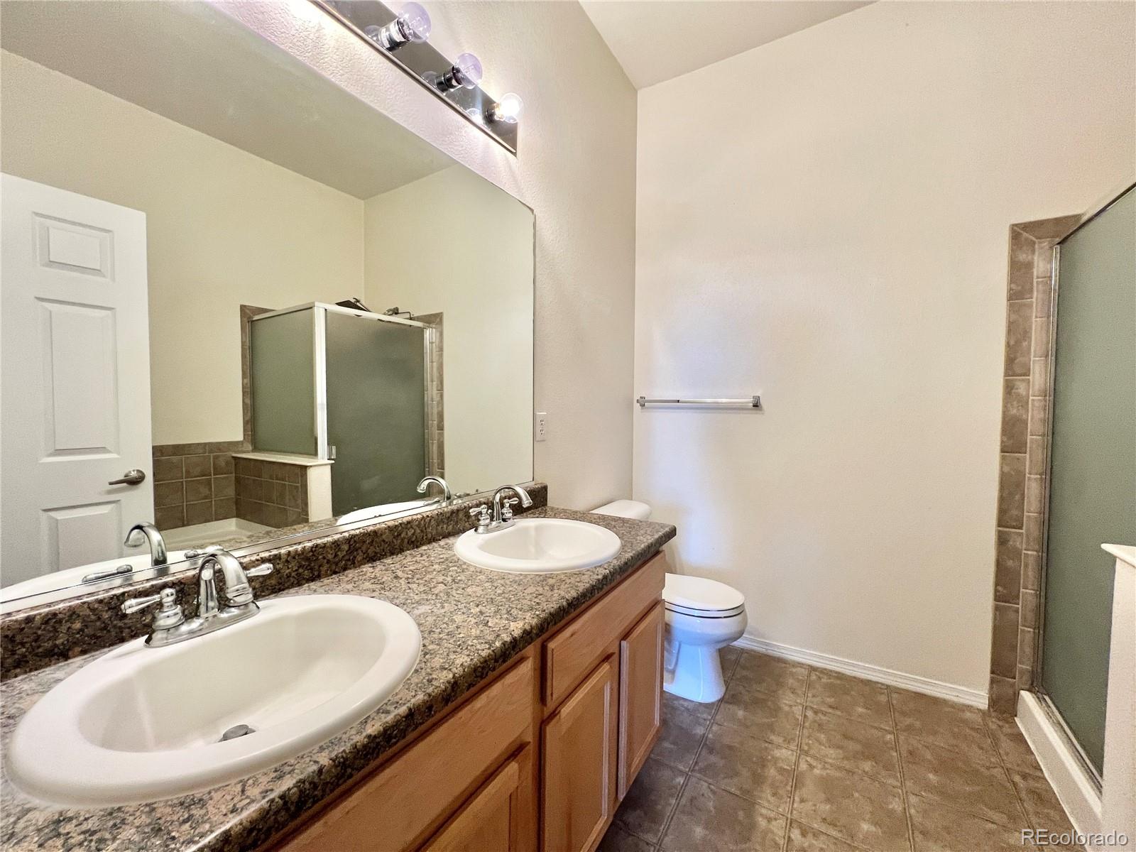 8467 Canyon Rim Circle, Unit 303 Parker, CO 80134 - Photo 14 of 17 a bathroom with a double vanity sink toilet and mirror