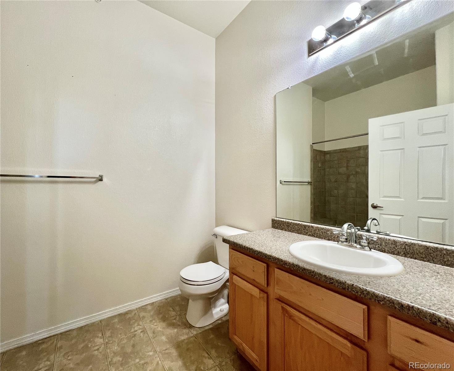 8467 Canyon Rim Circle, Unit 303 Parker, CO 80134 - Photo 6 of 17 a bathroom with a granite countertop sink a toilet and a mirror