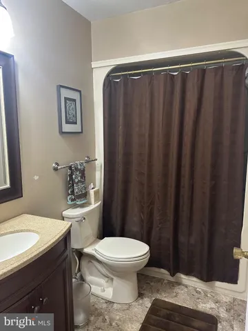 a bathroom with a granite countertop toilet and a sink
