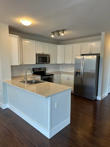 a kitchen with granite countertop a refrigerator and a stove top oven