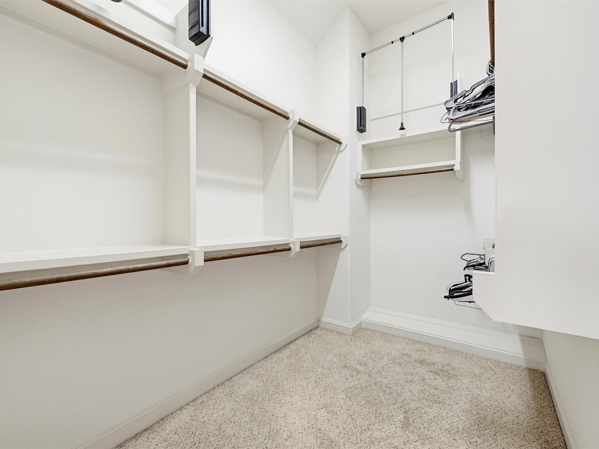9427 London Bridge Station Houston, TX 77045 - Photo 6 of 30 Discover a bright, spacious walk-in closet with ample shelving and hanging space, featuring neutral carpeting—a perfect haven for organizing your clothing and accessories.