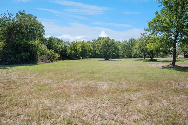 a view of outdoor space with a field and trees in the background