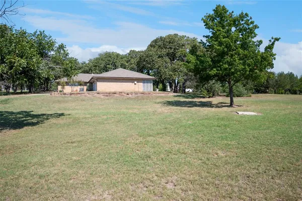 a front view of a house with yard outdoor seating and covered with trees