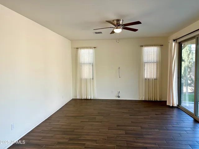 an empty room with wooden floor fan and windows