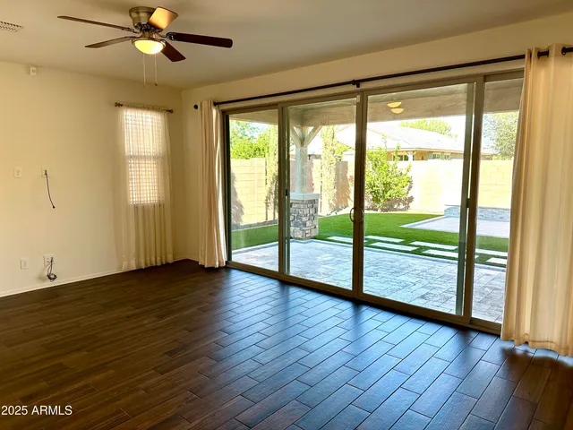 a view of empty room with wooden floor and fan