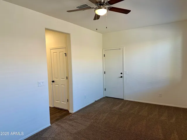 an empty room with a ceiling fan and carpet