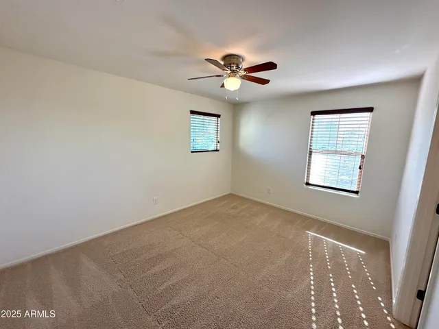 a view of a big room with windows and chandelier fan