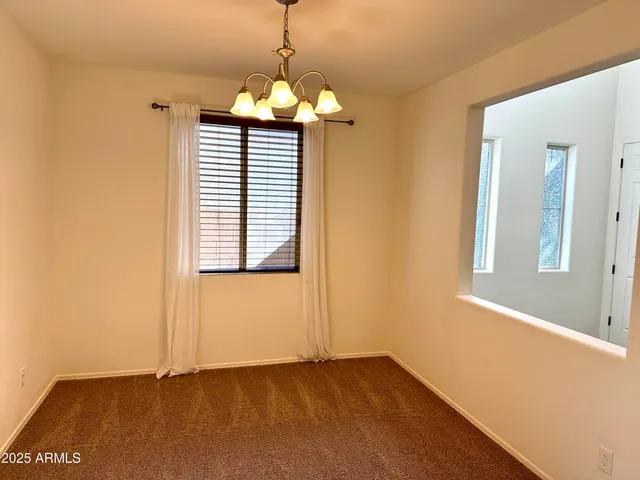 a view of an empty room with window and chandelier fan