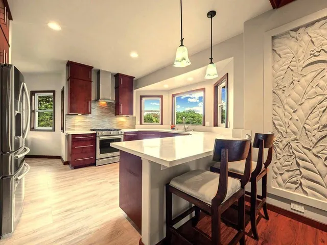 a view of kitchen with stainless steel appliances granite countertop table chairs and a large window