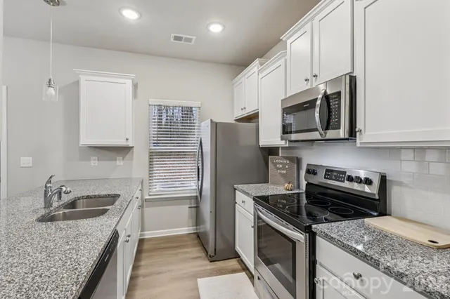 a kitchen with granite countertop a sink stainless steel appliances and cabinets