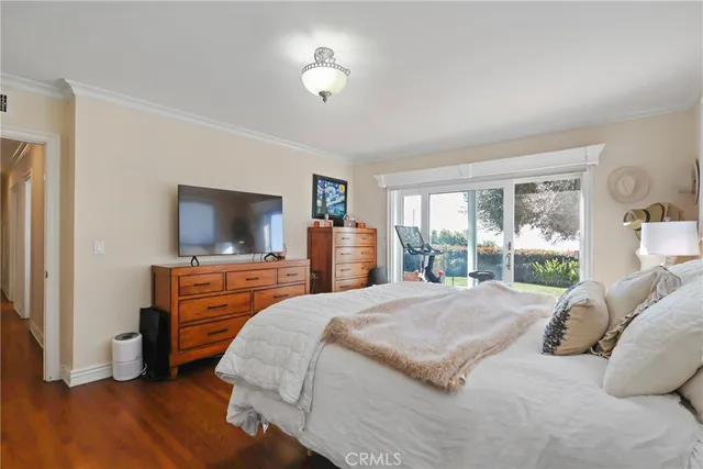 a bedroom with a large bed and a flat tv screen on dresser