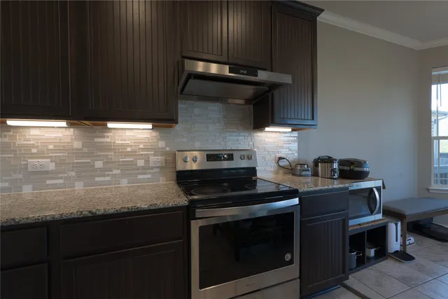 a kitchen with a stove a sink and chandelier