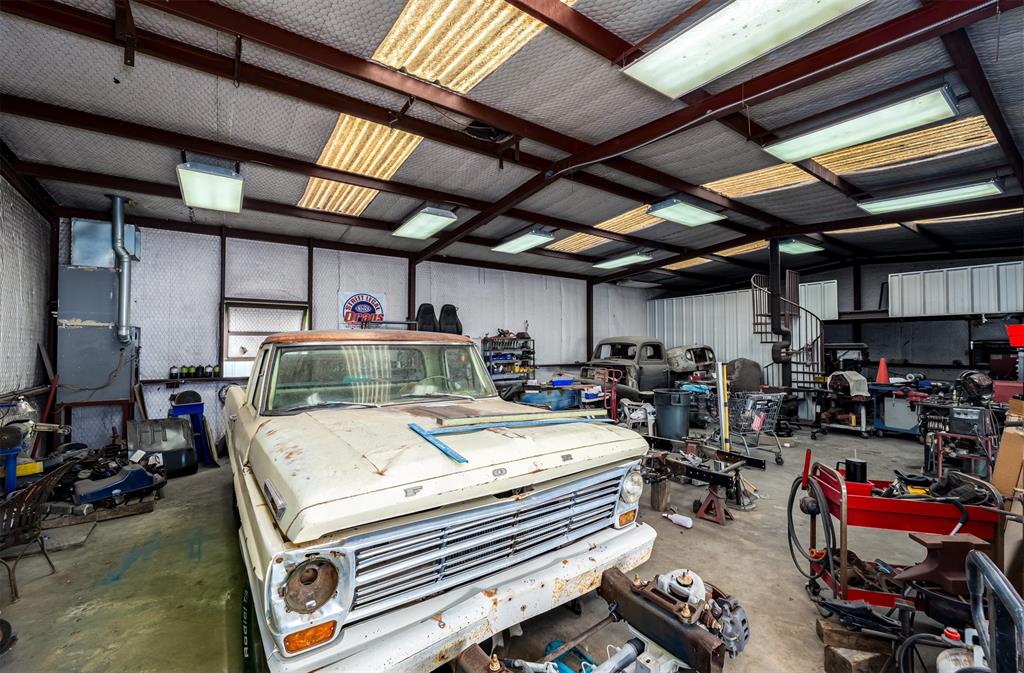 601 Houston School Road Red Oak, TX 75154 - Photo 18 of 32 Spacious workshop featuring a metal beam structure, corrugated metal roof panels, fluorescent lighting, and a spiral staircase