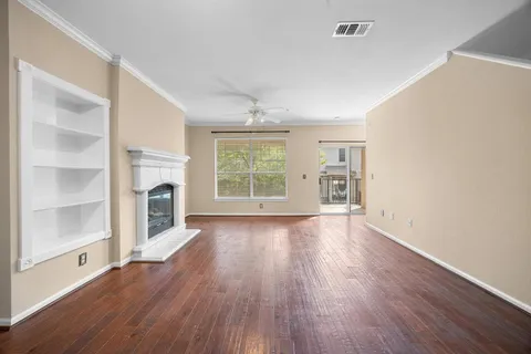 an empty room with wooden floor fireplace and windows