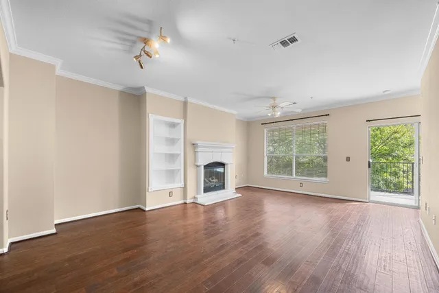 an empty room with wooden floor fireplace and windows