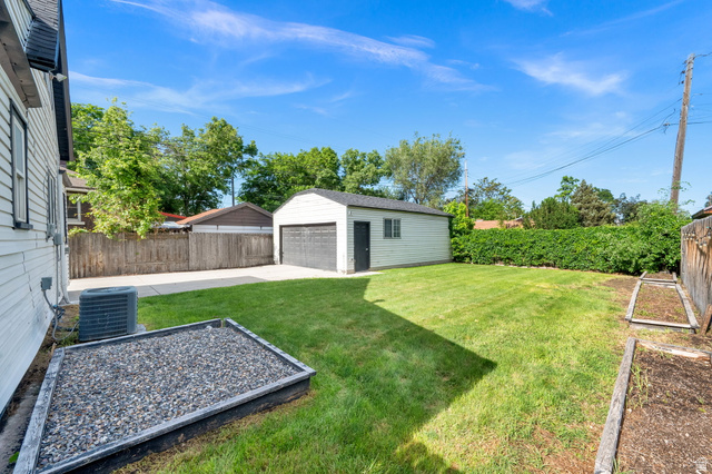 446 South 300 East Provo, UT 84606 - Photo 9 of 32 Expansive green lawn featuring a detached garage with a roll-up door, a gravel-filled planter box, and a privacy fence