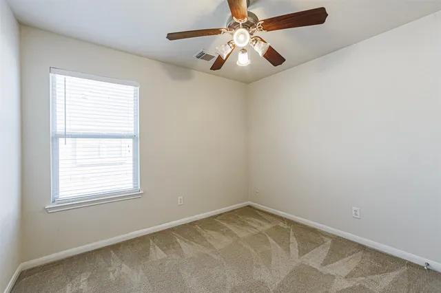 an empty room with a chandelier fan and windows