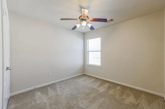 an empty room with windows and chandelier fan