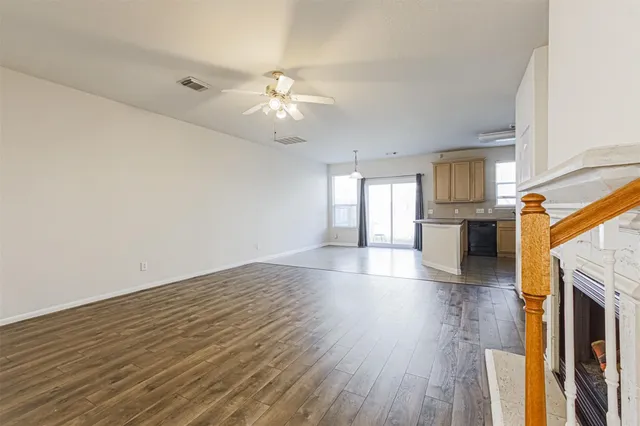an empty room with wooden floor fireplace and windows