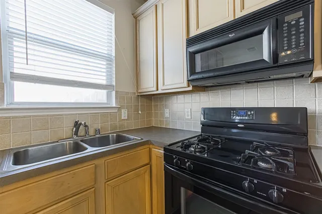 a kitchen with stainless steel appliances granite countertop white cabinets and a stove top oven