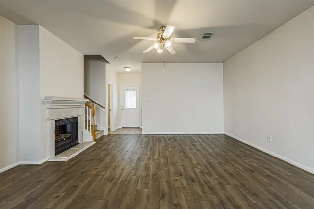 an empty room with wooden floor fireplace and windows