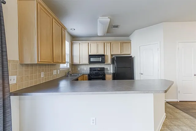 a kitchen with granite countertop a refrigerator a sink a stove and cabinets