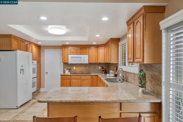 a kitchen with stainless steel appliances granite countertop a sink a stove and a refrigerator