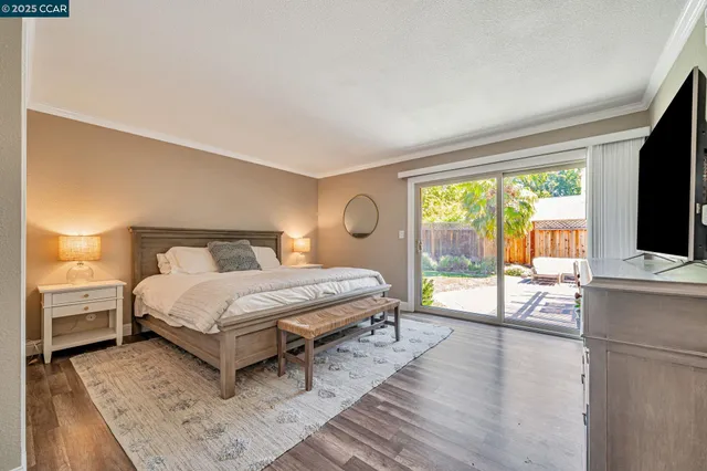 a spacious bedroom with a bed and a flat tv screen on dresser