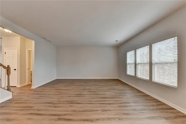 a view of empty room with wooden floor and floor to ceiling window