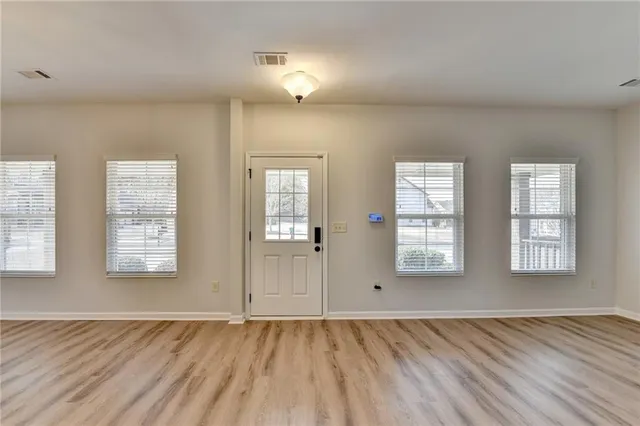 an empty room with wooden floor and windows