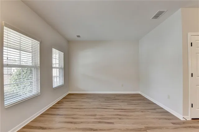 a view of an empty room with wooden floor and window