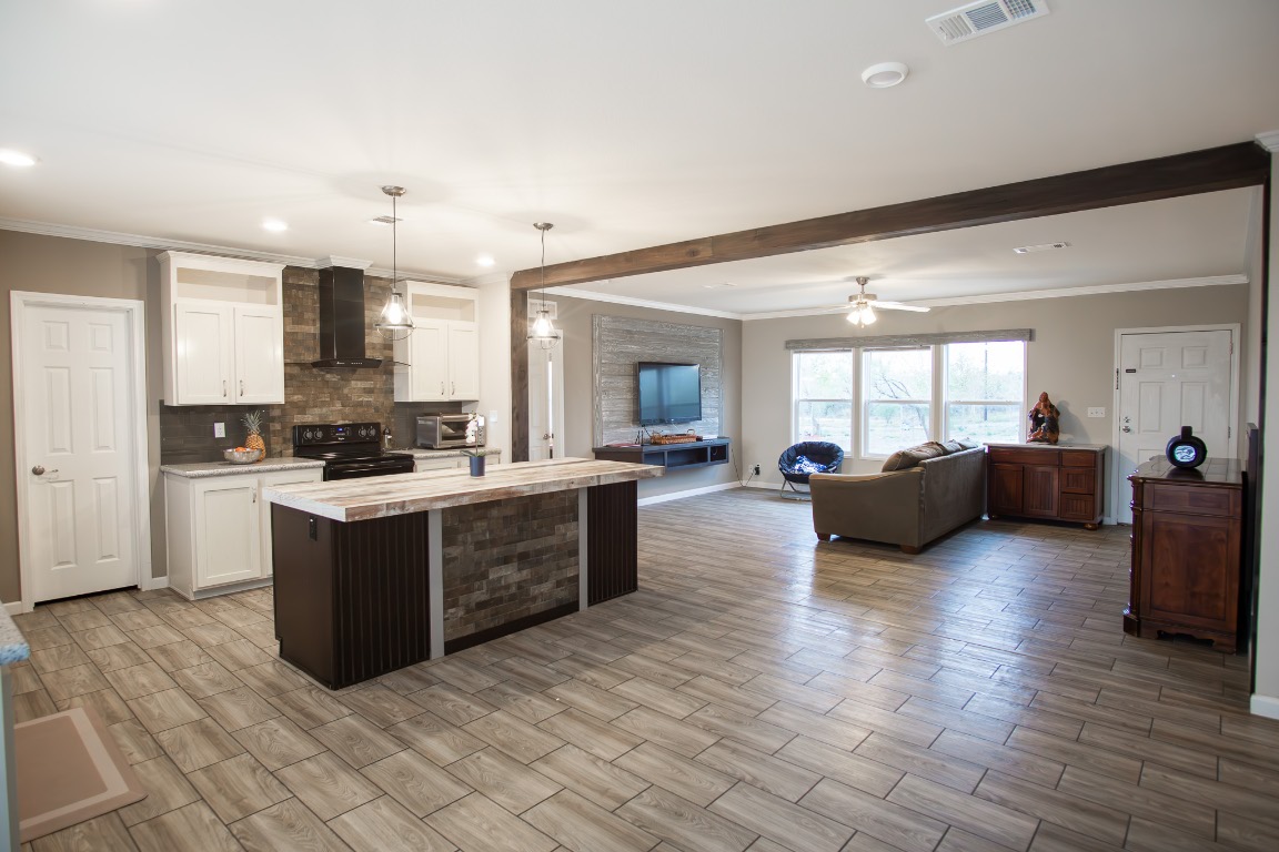 3882 Dry Creek Road Lockhart, TX 78644 - Photo 17 of 18 a large living room with stainless steel appliances kitchen island granite countertop a large cabinets and a wooden floor