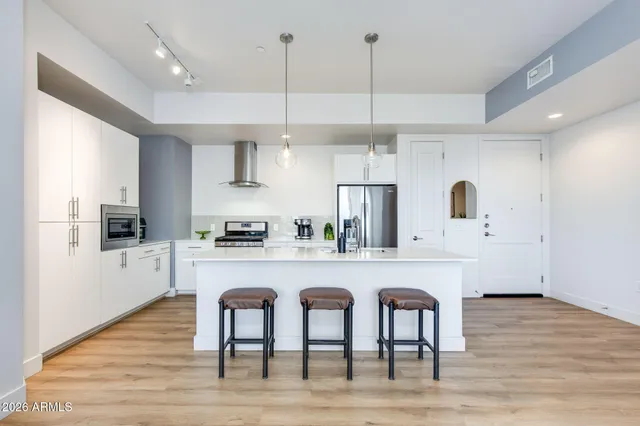 a kitchen with stainless steel appliances granite countertop a table chairs refrigerator and sink