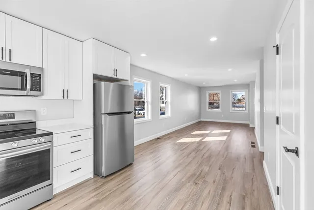 a kitchen with granite countertop a refrigerator stove and wooden floor